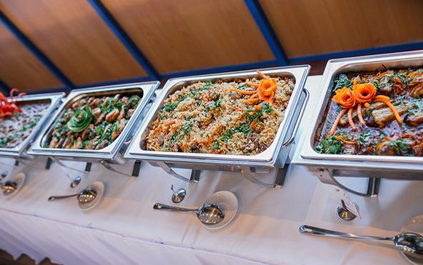 Professional baby shower buffet catering in Kolkata with stainless chafing dishes, curries, pulao, and garnished mains on white linen — Parsha Caterer