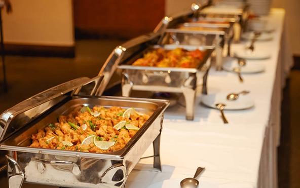 Long buffet line for baby shower catering in Kolkata with fish fry starters, curries in chafing dishes, plates and serving spoons — Parsha Caterer