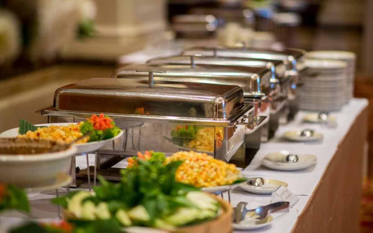 Conference and office event catering in Kolkata — elegant chafing-dish buffet with fresh salads and stacked plates by Parsha Caterer